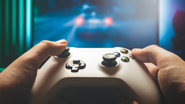 Sostiene un controlador de Xbox frente a la pantalla.