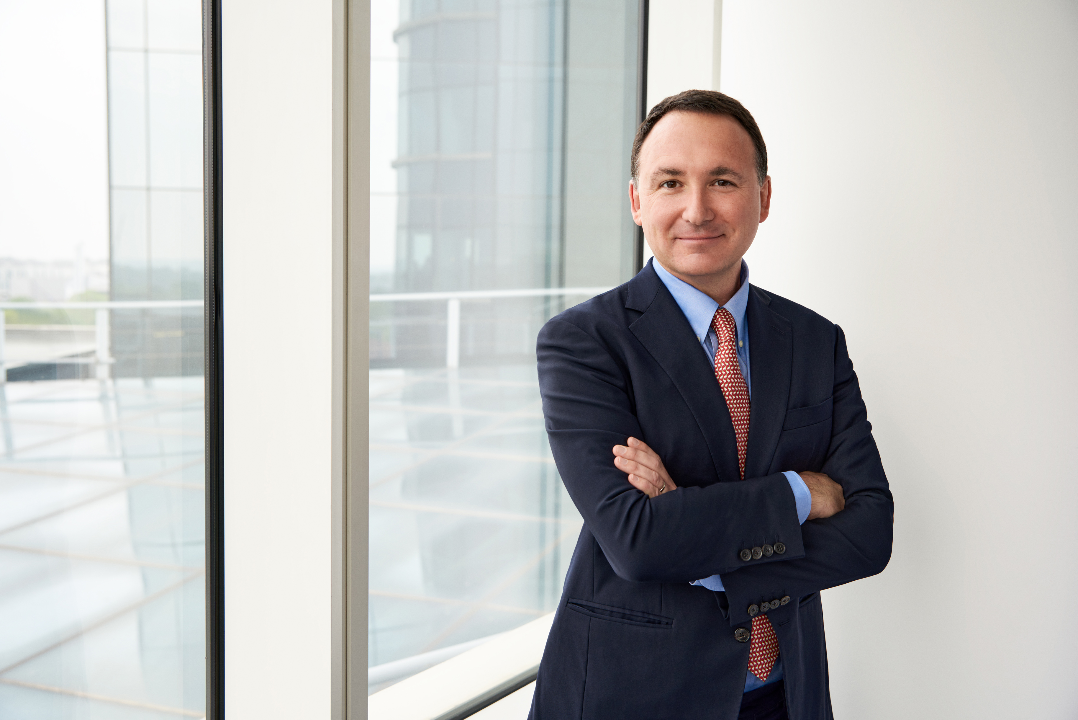 Luke Miels, director comercial de GlaxoSmithKline, sonríe con los brazos cruzados frente a la ventana.