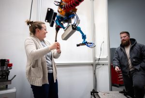 <strong>Hannah Sims, izquierda, y Levi Van Bastian</strong> <strong>instala un brazo robótico en un sistema de deposición directa de energía para la fabricación aditiva en las nuevas instalaciones CAMINO de Sandia National Laboratories. </strong>(Foto de Craig Fritz) Haga clic en la miniatura para ver la imagen de alta resolución.» class=»wp-image-114147″ data-description=»» data-title=»fabricación aditiva CAMINO» data-caption=»<figcaption class="título-elemento-wp"><strong>Hannah Sims, izquierda, y Levi Van Bastian</strong> <strong>ajustan un brazo robótico en un sistema de deposición directa de energía para la fabricación aditiva en las nuevas instalaciones CAMINO de Sandia National Laboratories. </strong>(Foto de Craig Fritz) Haga clic en la miniatura para ver una imagen de alta resolución.</figcaption>»  tamaños=»(ancho máximo: 300px) 100vw, 300px»/><figcaption class=