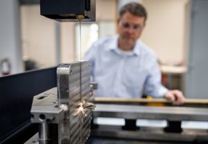 <strong>Dale Cillessen utiliza una máquina de descarga eléctrica de alambre para cortar una muestra de metal en las instalaciones CAMINO de Sandia National Laboratories. </strong> (Foto: Craig Fritz) Haga clic en la miniatura para ver la imagen de alta resolución.» class=»wp-image-114151″ data-description=»» data-title=»fabricación aditiva CAMINO» data-caption=»<figcaption class="título-elemento-wp"><strong>Dale Cillessen utiliza una máquina de descarga eléctrica de alambre para cortar una pieza de muestra de metal en las instalaciones CAMINO de Sandia National Laboratories. </strong> (Foto de Craig Fritz) Haga clic en la miniatura para ver una imagen de alta resolución.</figcaption>»  tamaños=»(ancho máximo: 300px) 100vw, 300px»/><figcaption class=