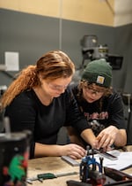 En esta foto del Central Oregon Community College, Avery Smith (izquierda) y Sydon Kofal usan un micrómetro para medir algunos de los procesos de fabricación en el laboratorio de tecnología de fabricación de Redmond, Oregon, en noviembre de 2024.