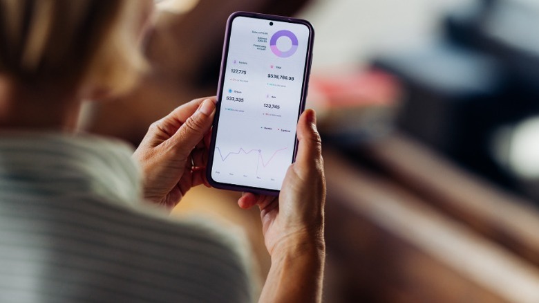 Una mujer mira la información del mercado de robo-advisor en una aplicación de teléfono.