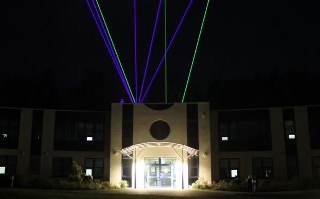 Láseres que emergen del techo de un edificio por la noche.