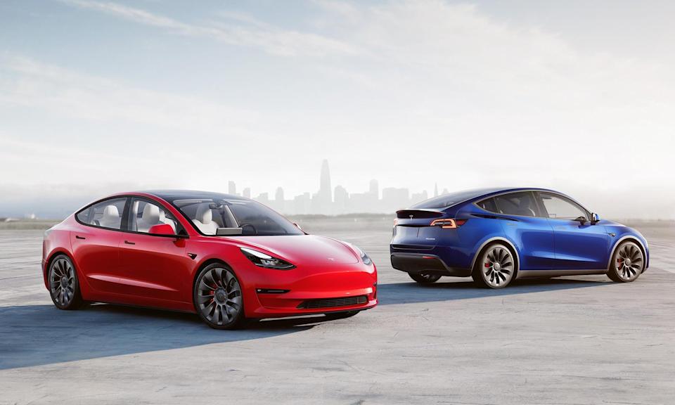 Dos Teslas estacionados uno cerca del otro afuera, con el horizonte al fondo.